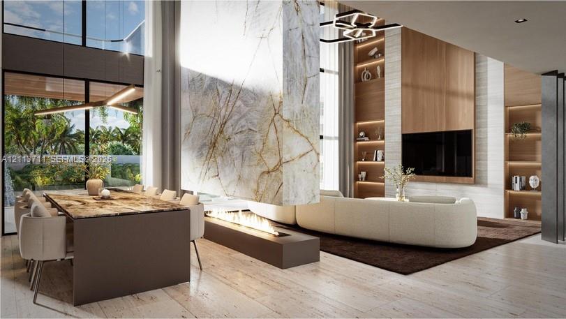 Double-height ceilings, stone-clad dual-sided fireplace, floor-to-ceiling windows, custom built-in wood shelving, and stone flooring