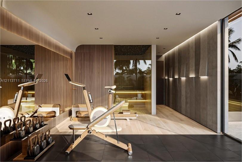 Wood-finish wall paneling, integrated recessed ceiling lighting, large-format matte floor tiling, full-height mirror wall, and glass-enclosed sauna with tiered bench seating