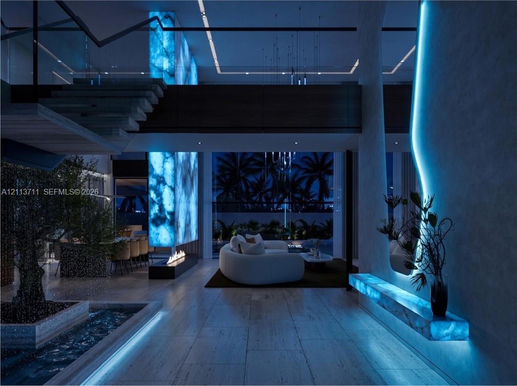 Open-concept interior featuring large-format stone flooring, back-lit stone column, linear fireplace, and integrated LED wall accent