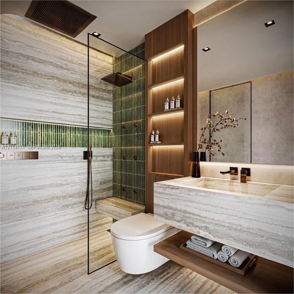Stone-tiled bathroom featuring a glass-enclosed walk-in shower with integrated wall-mounted shower heads, vertical green tile accents, wood-finish built-in shelving with recessed lighting, and a wall-mounted floating vanity