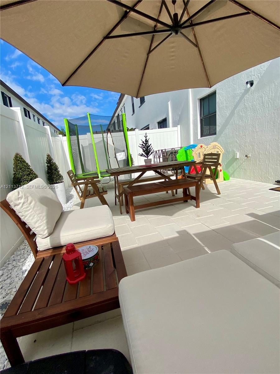 Private courtyard featuring light-toned paver flooring and white vinyl privacy fencing