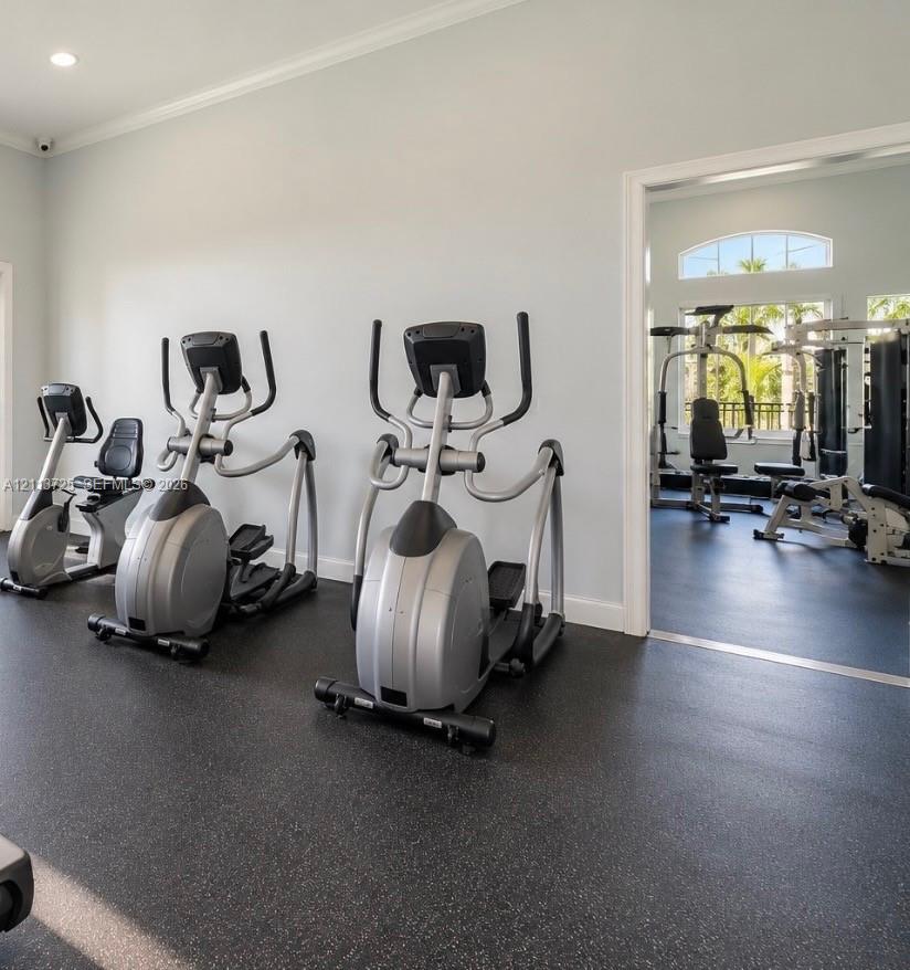 Fitness room featuring durable rubber flooring, recessed lighting, and arched windows