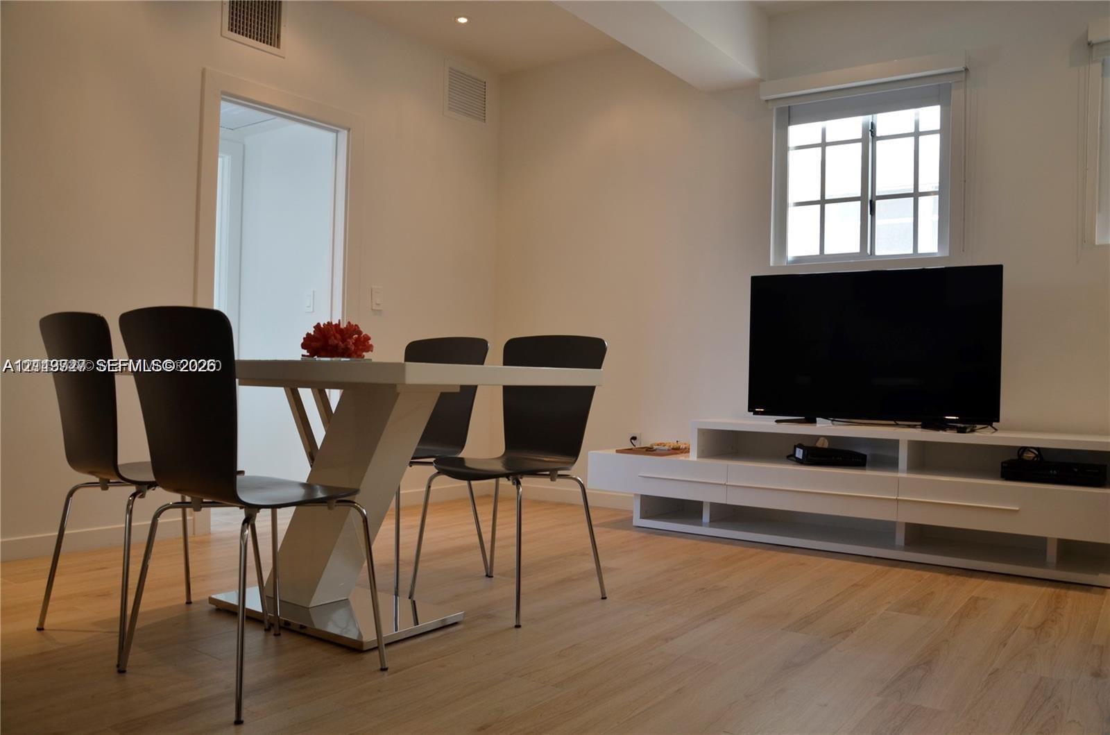 Interior space featuring wood-finish flooring, recessed ceiling lighting, a multi-pane window, and a built-in floating media console Interior space featuring wood-finish flooring, recessed ceiling lighting, a multi-pane window, and a built-in floating media console