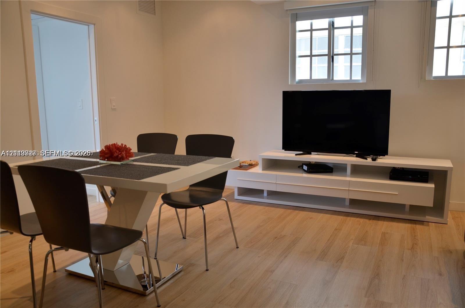 Neutral interior featuring light-tone wood-finish flooring, white built-in media cabinetry, and double-hung windows with mullions Neutral interior featuring light-tone wood-finish flooring, white built-in media cabinetry, and double-hung windows with mullions