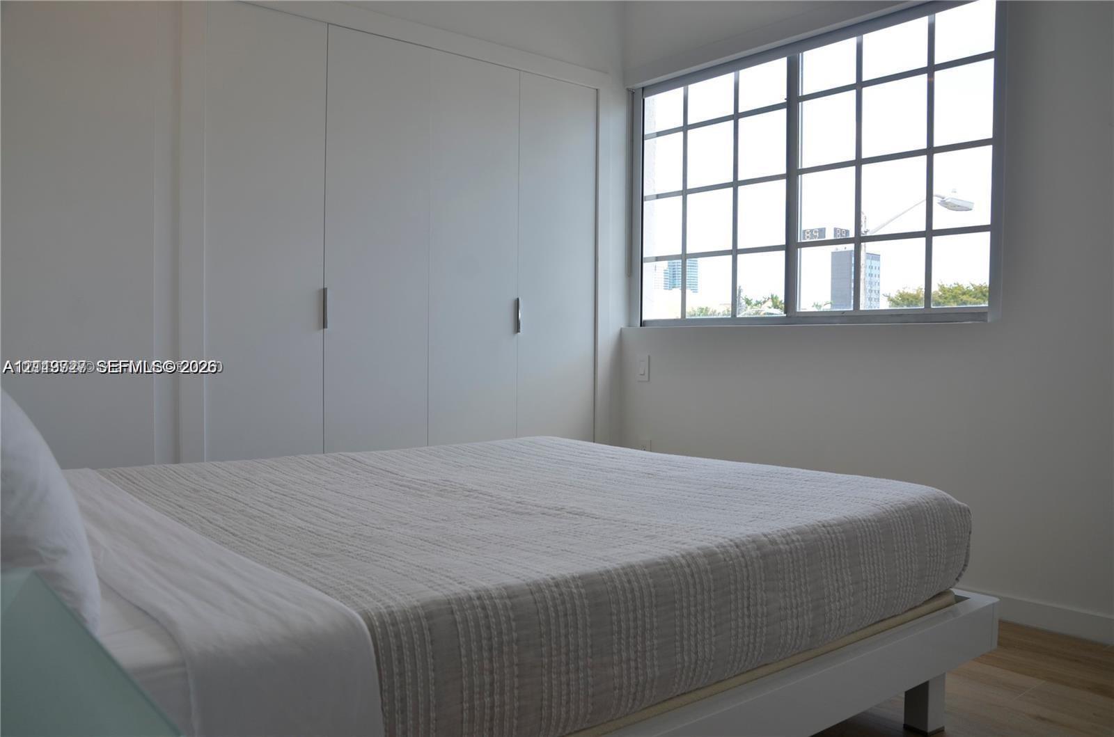 Wall-to-wall built-in closet with clean-lined doors, grid-pattern window, and neutral interior finish