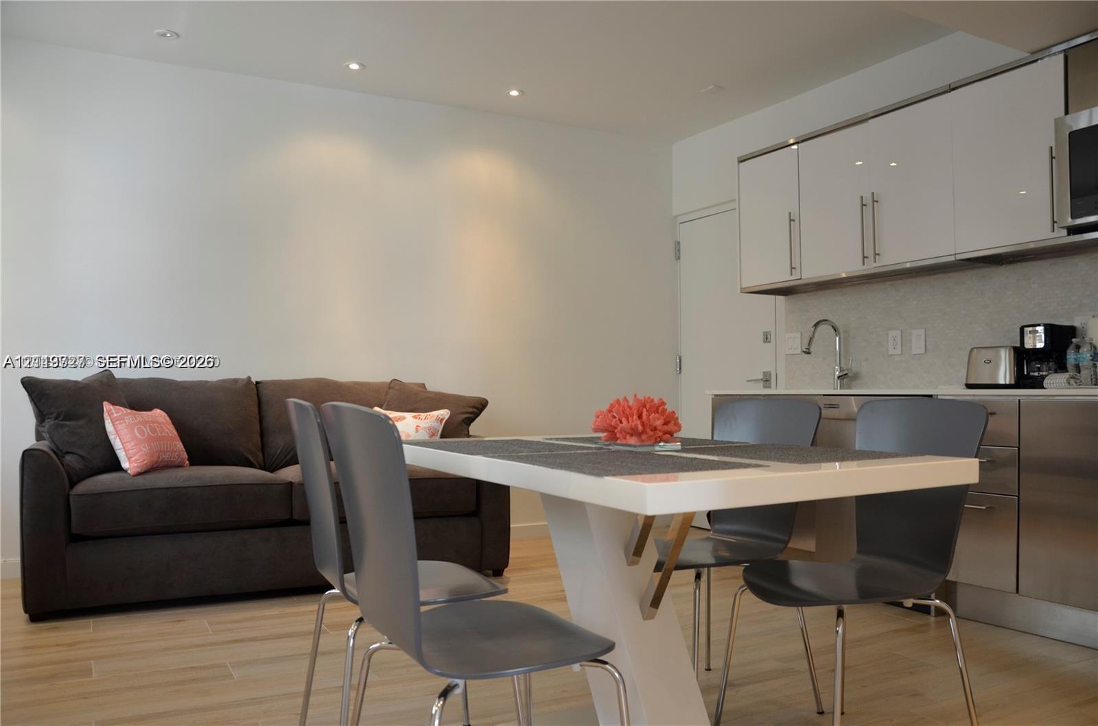 Kitchen area featuring high-gloss cabinetry, stainless steel lower cabinets, recessed lighting, and wood-finish flooring Kitchen area featuring high-gloss cabinetry, stainless steel lower cabinets, recessed lighting, and wood-finish flooring