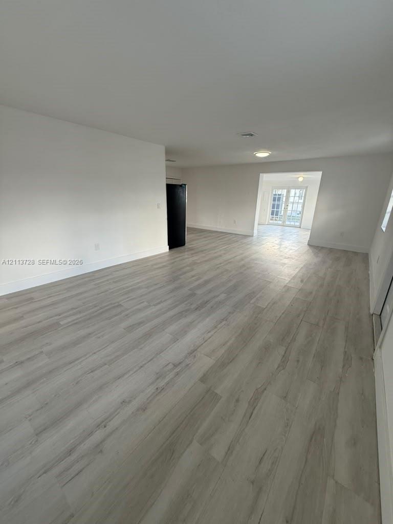 Open-concept interior featuring wood-finish flooring, recessed lighting, and white walls, complete with a glass-paned double door entrance Open-concept interior featuring wood-finish flooring, recessed lighting, and white walls, complete with a glass-paned double door entrance