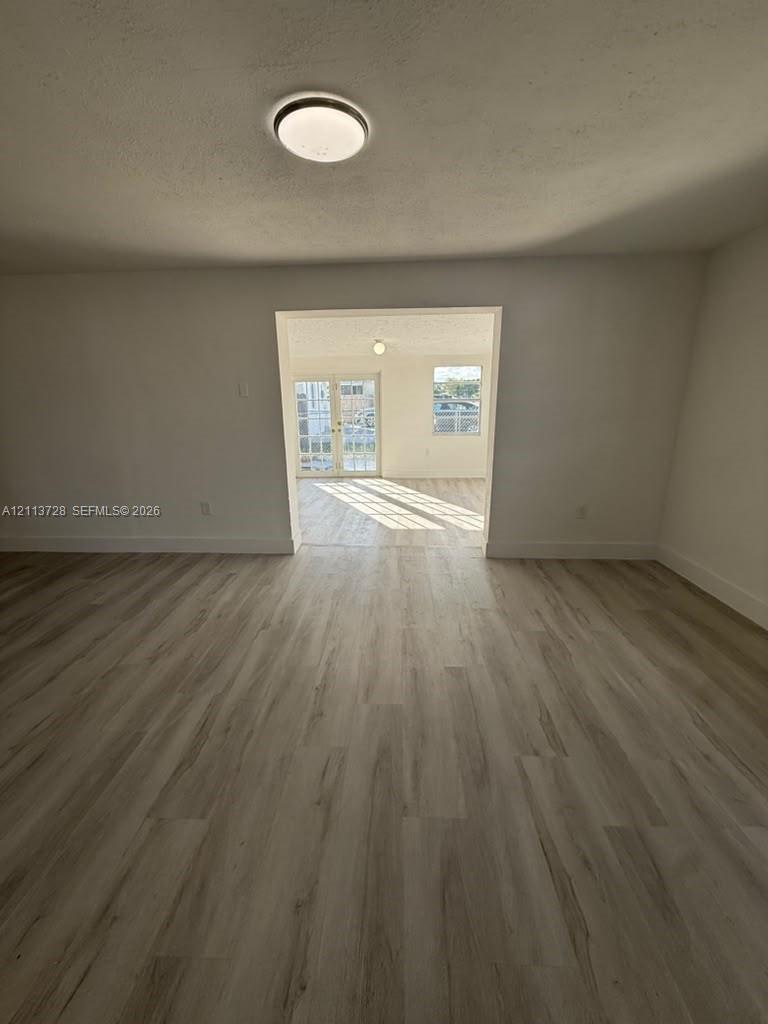 Neutral-toned wood-finish flooring, flush-mount ceiling light fixture, and glass-paneled double doors