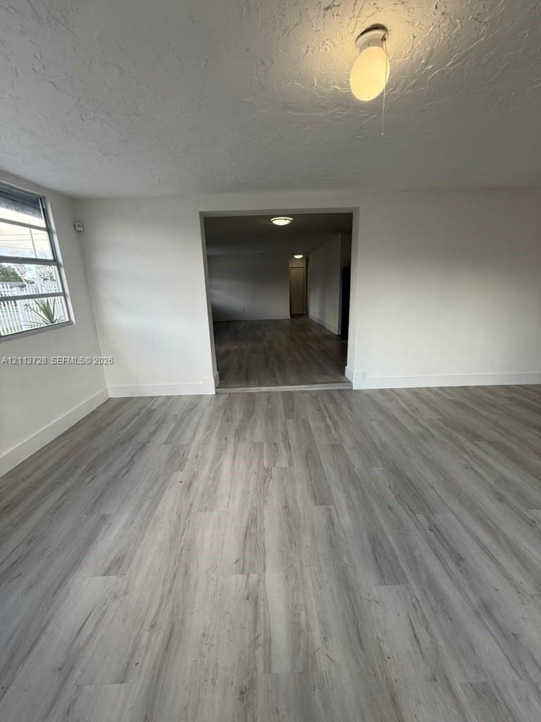 Neutral-toned wood-finish flooring, multi-pane window with metal frame, and ceiling-mounted light fixtures