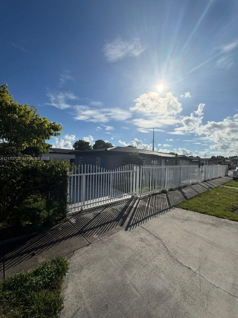 Exterior of a single-story residence featuring a perimeter metal privacy fence and gated driveway access Exterior of a single-story residence featuring a perimeter metal privacy fence and gated driveway access