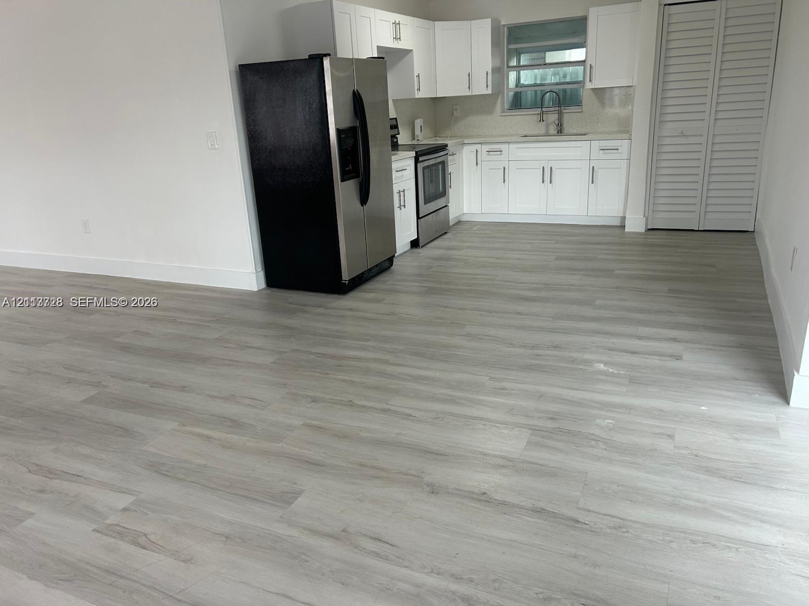 Kitchen featuring white shaker-style cabinetry, wood-finish flooring, stainless steel appliances, and a recessed faucet