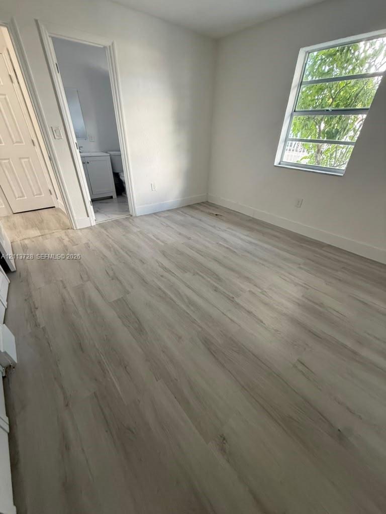Room featuring wood-finish flooring, a multi-pane window, and a multi-panel interior door