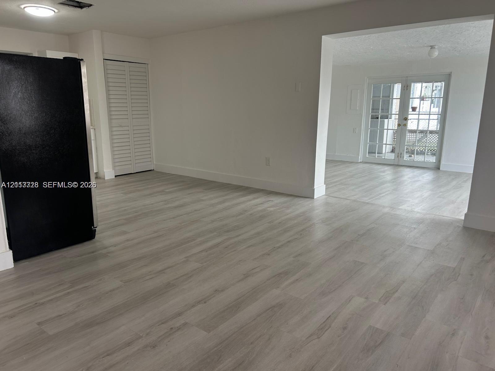 Wood-finish flooring, white louvered closet doors, and French doors with glass panes