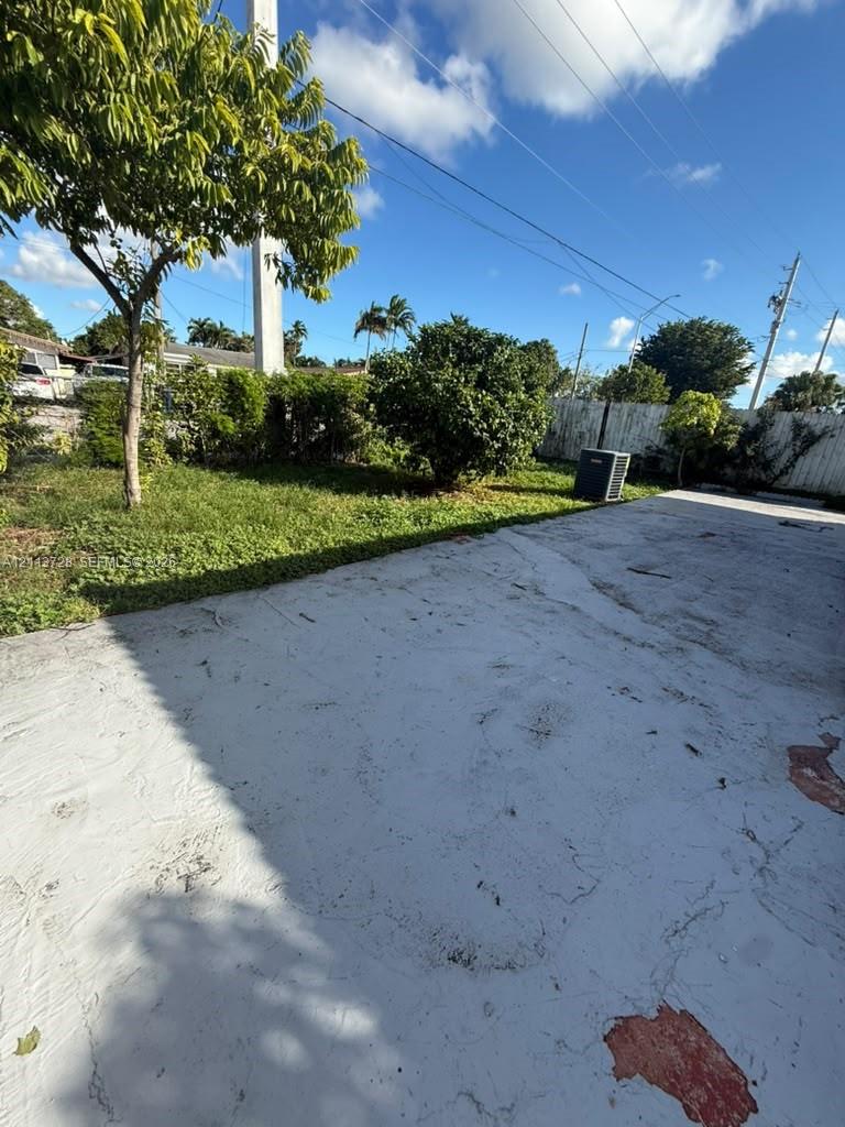 Concrete patio featuring a perimeter of mature landscaping and a privacy fence