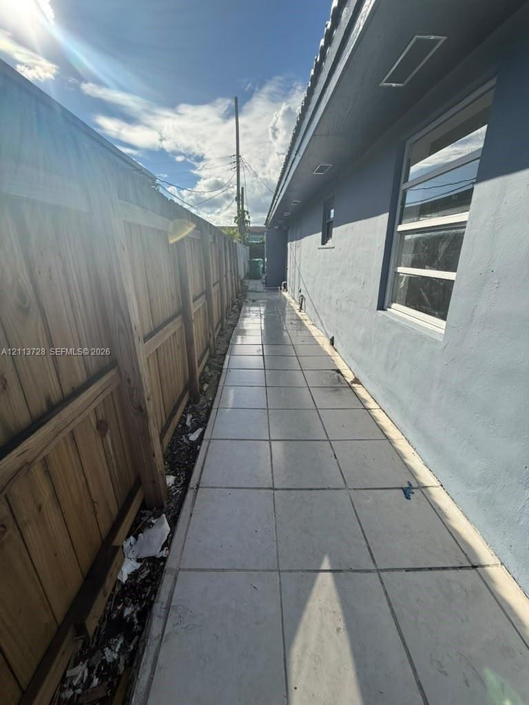 Exterior side yard featuring large-format tile paving and a wood-slat privacy fence