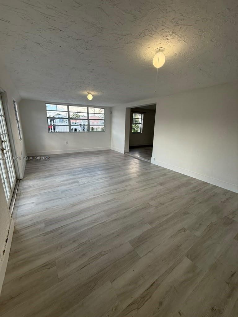 Interior space featuring wood-finish flooring, multi-pane windows, smooth-finish ceiling, and dual flush-mount light fixtures