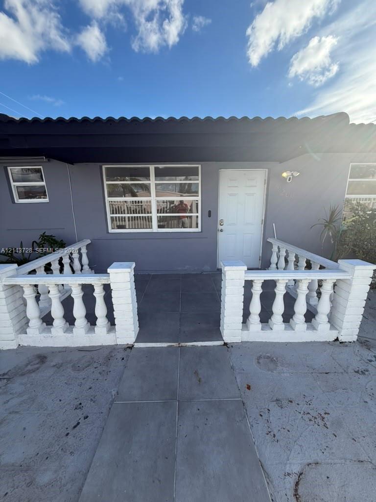 Exterior facade featuring a concrete porch with white decorative balustrades, large horizontal-pane windows, and a solid-core entry door Exterior facade featuring a concrete porch with white decorative balustrades, large horizontal-pane windows, and a solid-core entry door