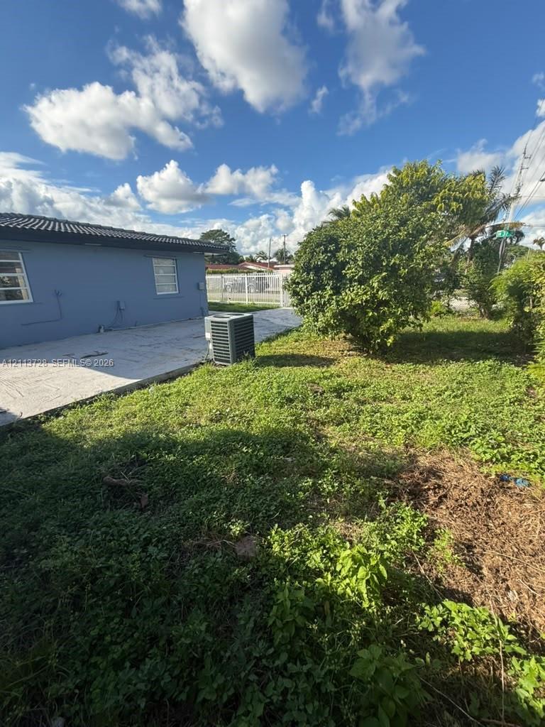 Exterior grounds featuring a concrete patio, perimeter chain-link fencing, and mature vegetation