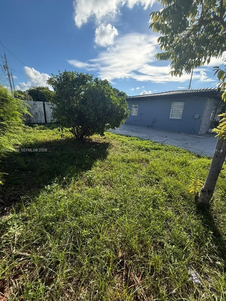 Exterior grounds featuring a concrete driveway, mature trees, and a concrete perimeter fence