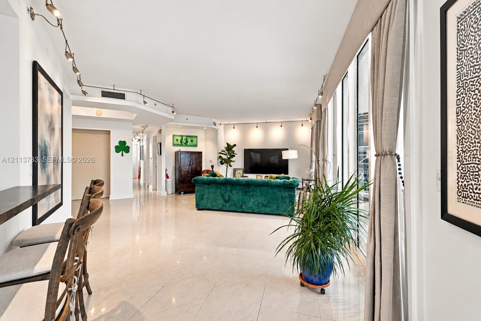 Polished stone flooring, floor-to-ceiling windows, built-in track lighting, and a breakfast bar