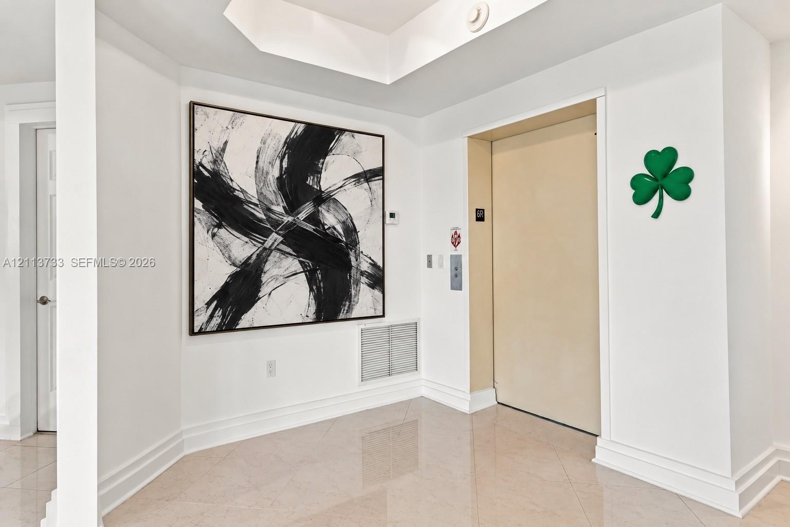 Foyer featuring large-format tile flooring, tray ceiling, and a private elevator access point