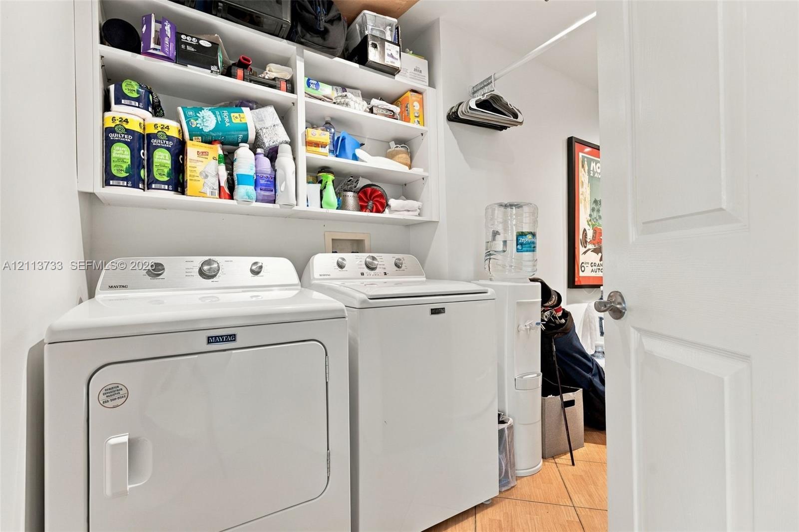 Private Utility space featuring tile flooring, built-in open shelving, and a wall-mounted clothing rod