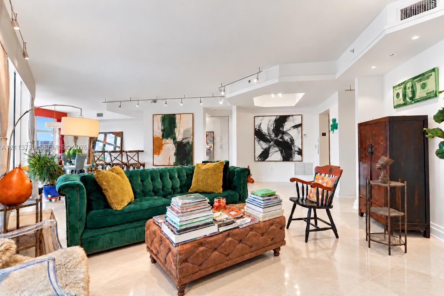 Open-concept interior featuring large-format polished stone flooring, adjustable track lighting, and a multi-tiered recessed ceiling