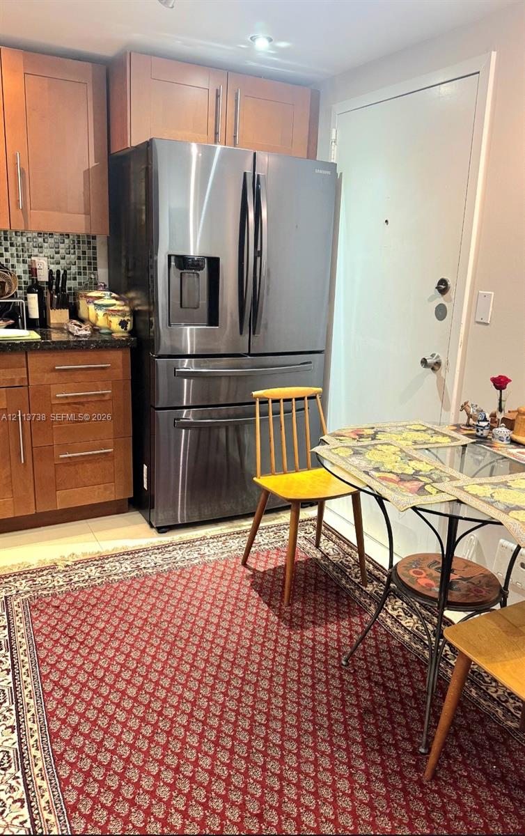 Kitchen featuring flat-panel wood cabinetry, dark stone countertops, mosaic tile backsplash, stainless steel French-door refrigerator, and recessed lighting