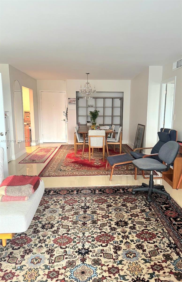 Living area featuring polished stone-finish flooring, built-in recessed shelving, and a hanging crystal chandelier