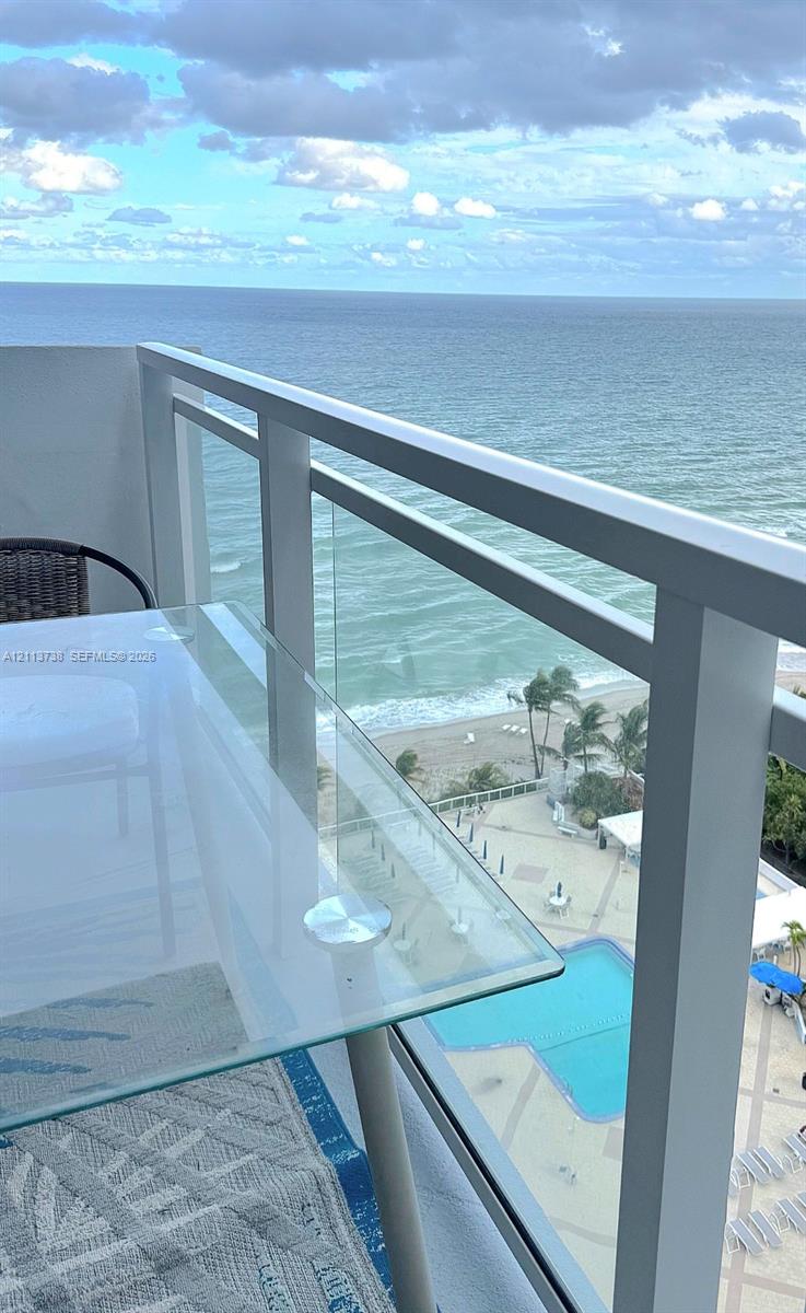 Private balcony featuring a glass-panel railing and direct oceanfront exposure