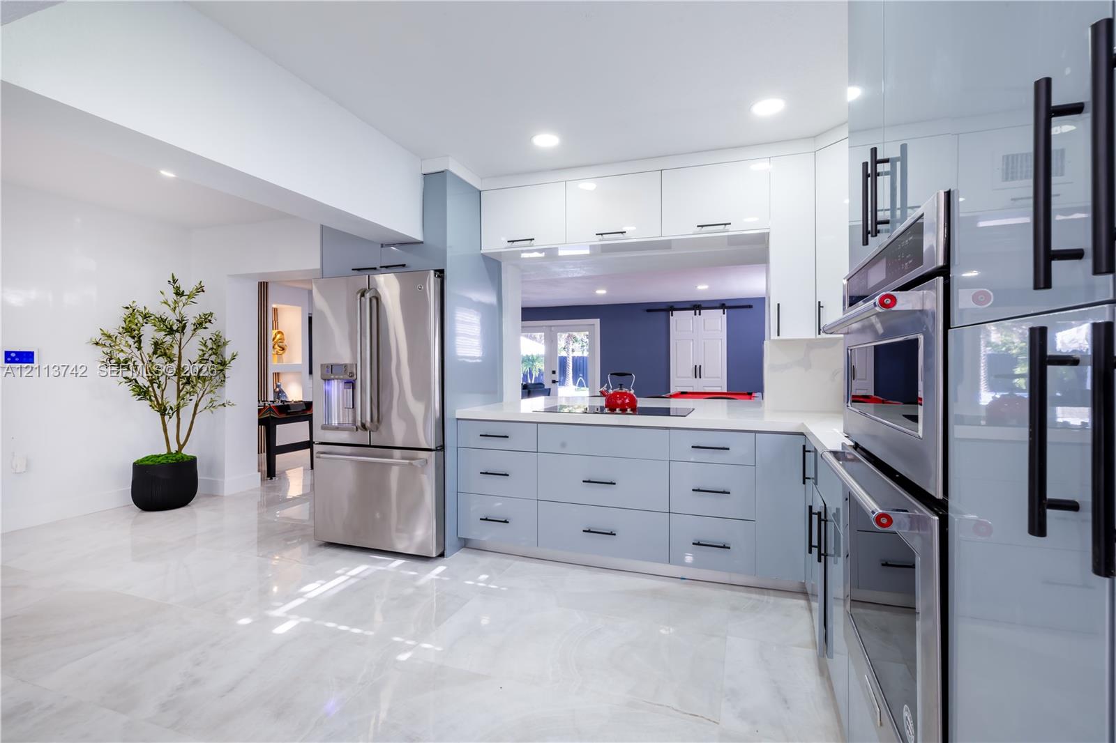 Kitchen featuring high-gloss cabinetry with matte black hardware, stone-finish flooring, stainless steel built-in appliances, and recessed lighting