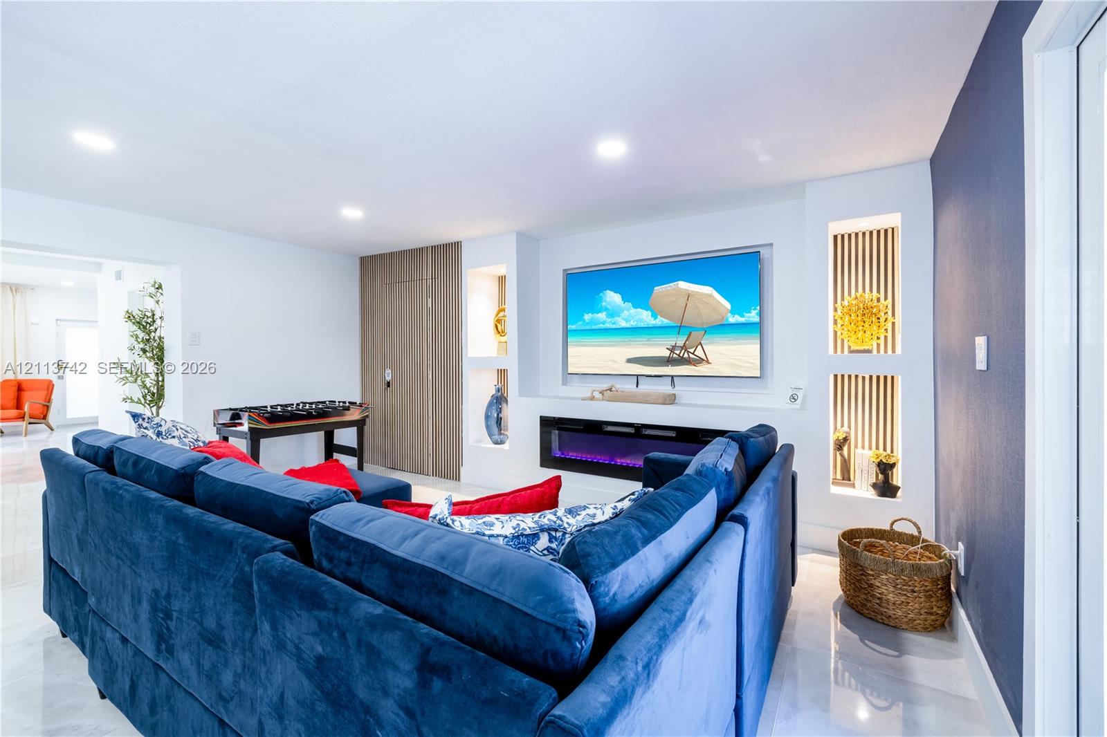 Recessed media wall featuring an electric fireplace, built-in shelving, slat-style accent paneling, and recessed lighting