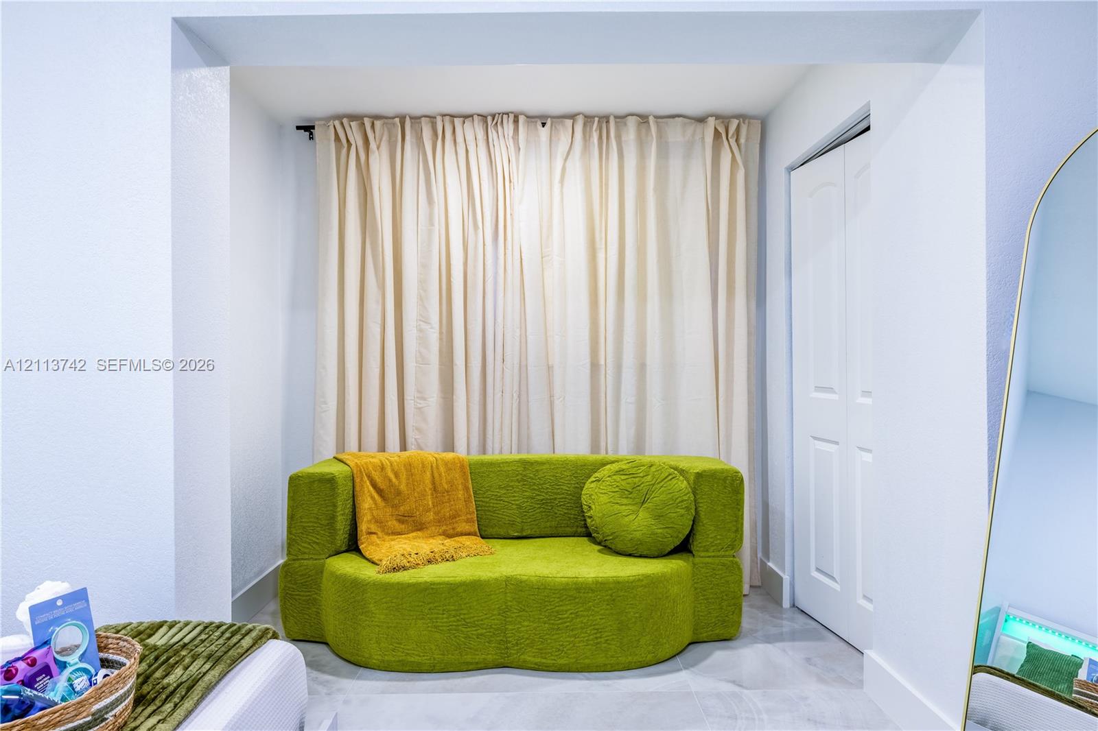 Recessed nook featuring light-toned tile flooring and a bi-fold closet door