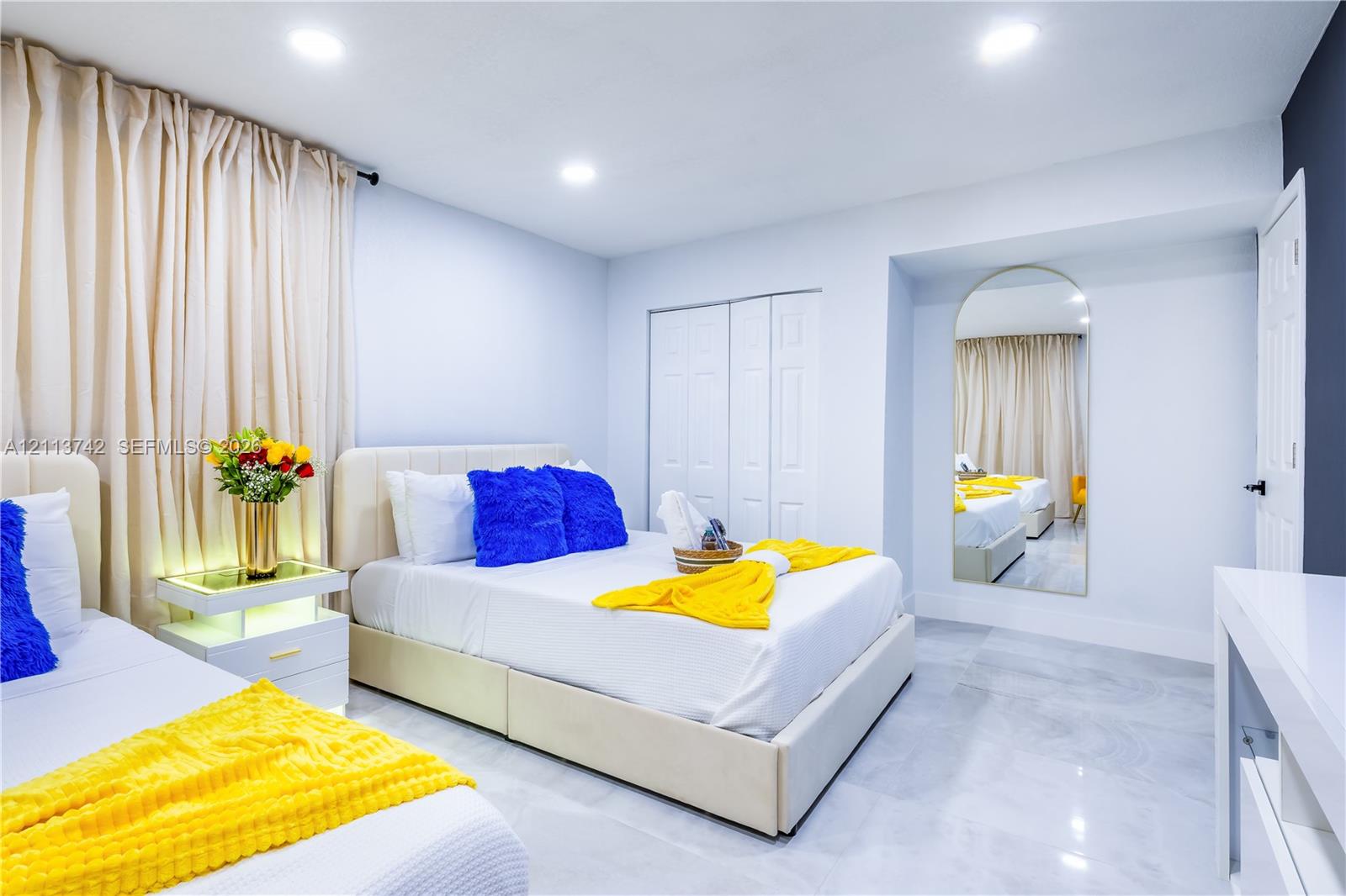 Neutral wall finish, polished stone-finish flooring, recessed lighting, double-door closet with paneled detail, and integrated arch-top wall mirror