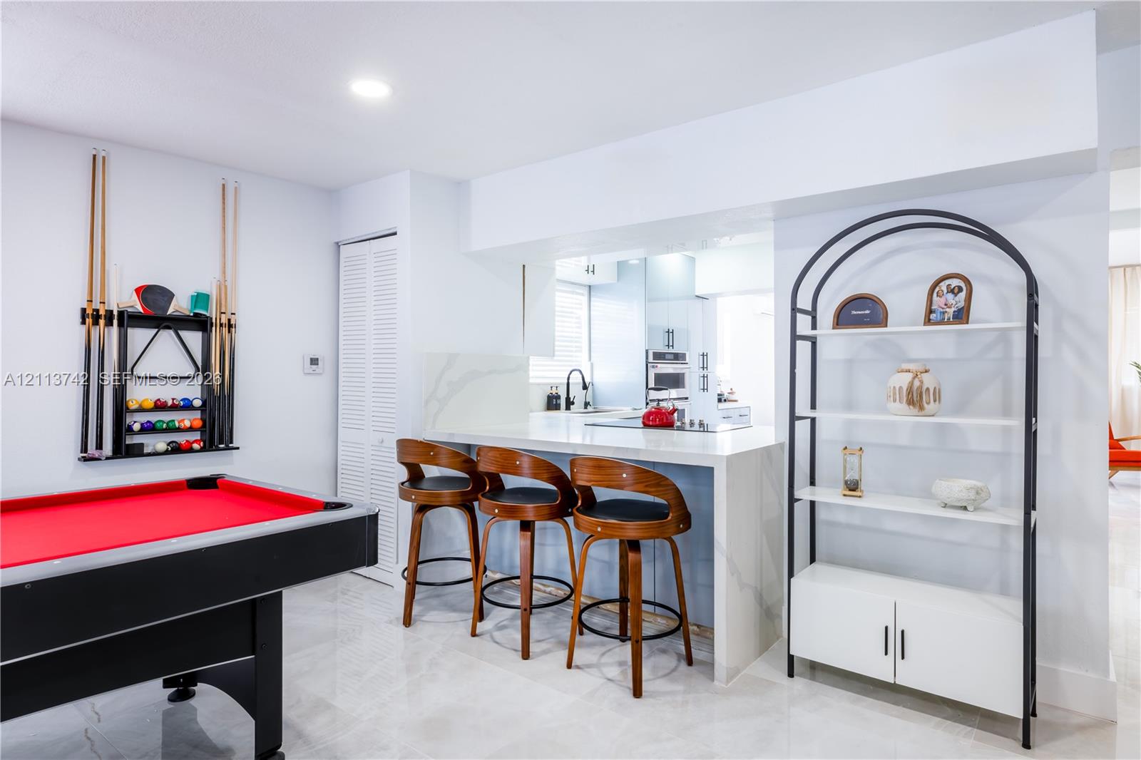 Kitchen peninsula featuring a stone-look waterfall countertop, light-reflective stone-finish flooring, and recessed ceiling lighting