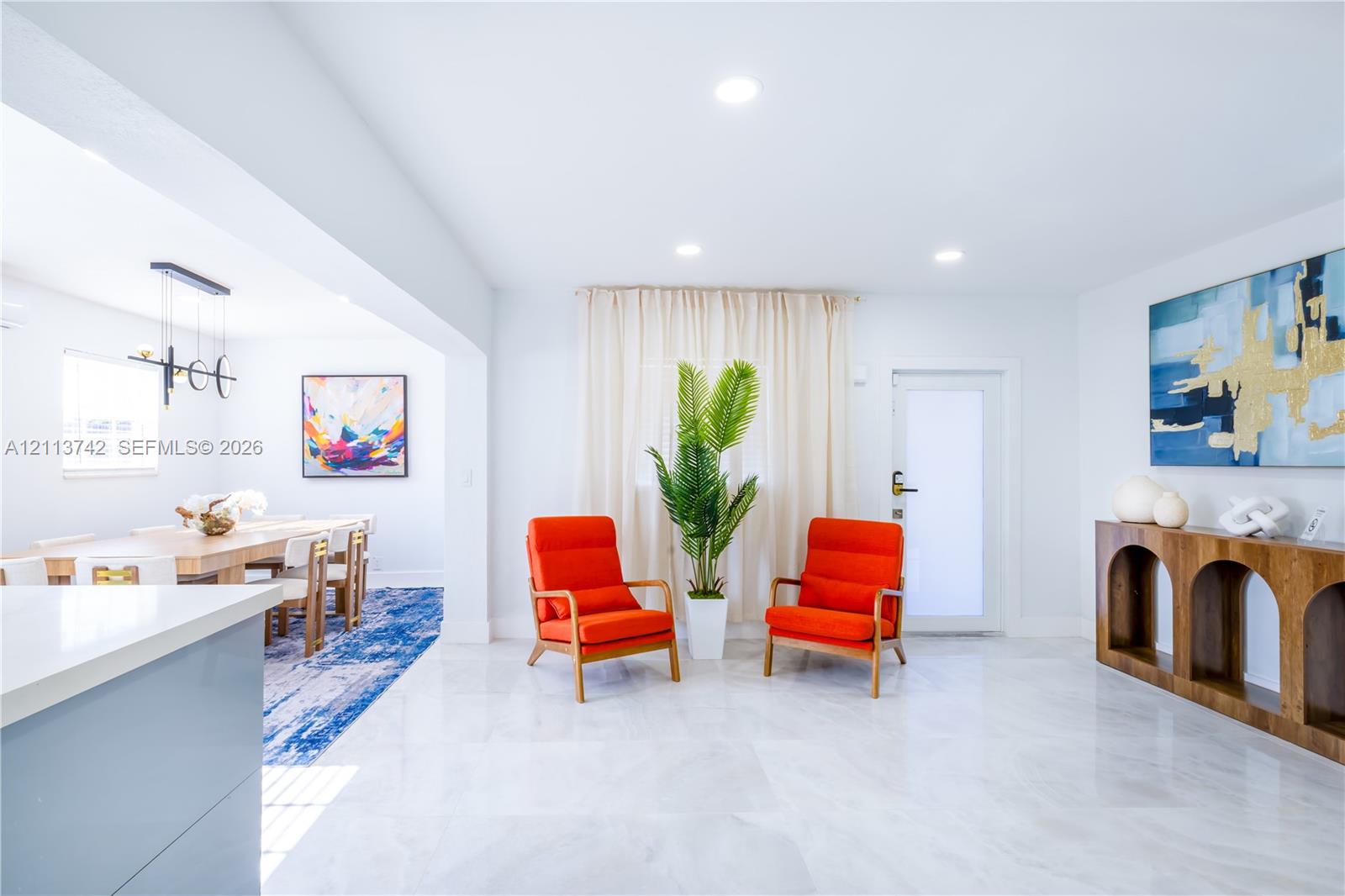 Open-concept interior featuring light-toned tile flooring, recessed ceiling lighting, and a modern tiered linear chandelier