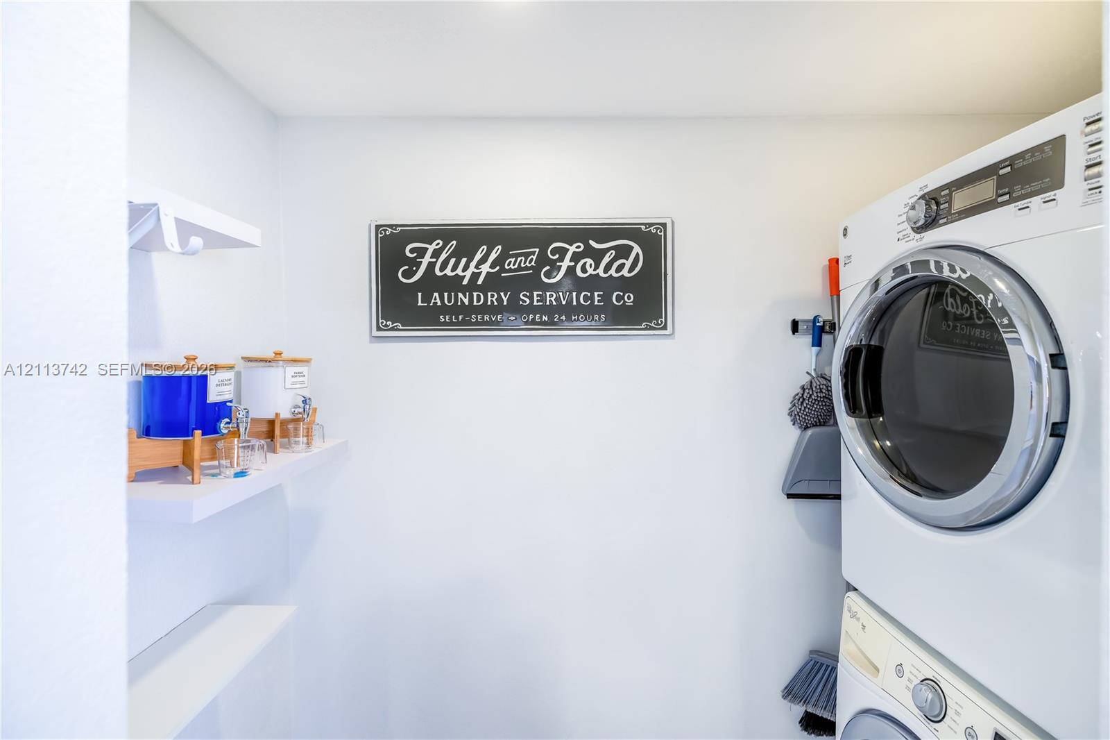 Laundry area featuring a white stackable washer and dryer unit and built-in white wall-mounted shelving