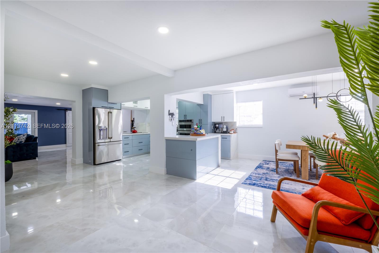 Kitchen featuring a central island with a solid-surface countertop, high-gloss cabinetry, recessed lighting, and stainless steel appliances, complemented by large-format polished flooring Kitchen featuring a central island with a solid-surface countertop, high-gloss cabinetry, recessed lighting, and stainless steel appliances, complemented by large-format polished flooring