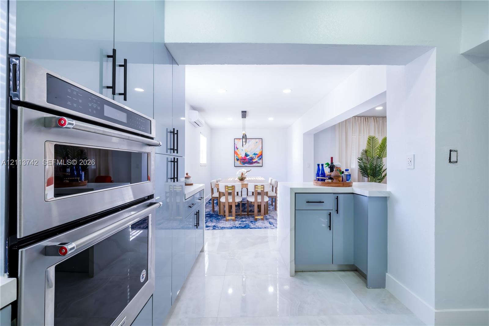 Kitchen featuring high-gloss blue cabinetry, built-in stainless steel wall oven, recessed ceiling lighting, and tile flooring