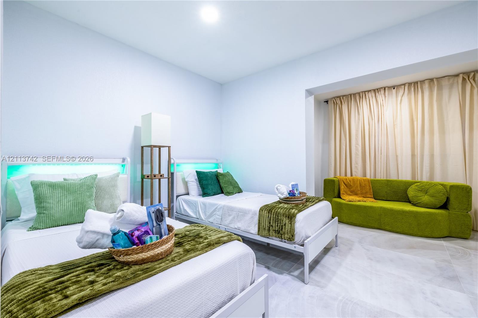 Spacious interior featuring large-format light-tone tile flooring, recessed ceiling lighting, and a recessed window nook with full-length drapery