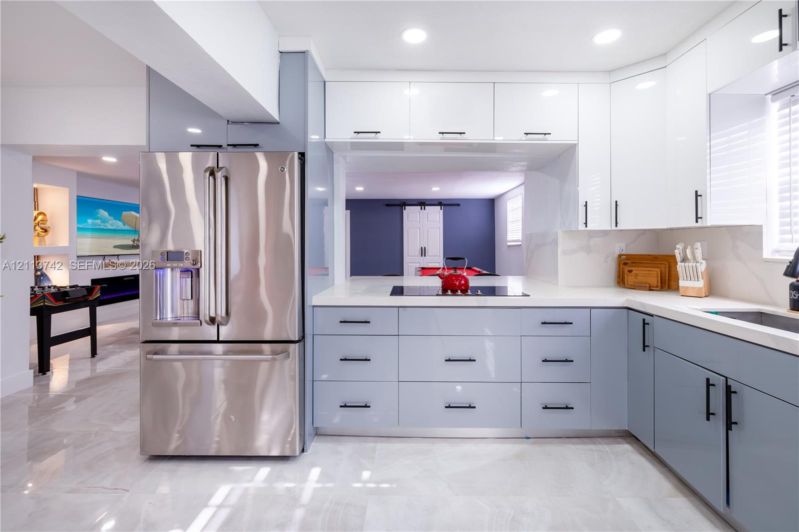 Kitchen featuring gloss-finish cabinetry, stone-surface countertops, integrated stainless steel appliances, recessed lighting, and large-format tile flooring