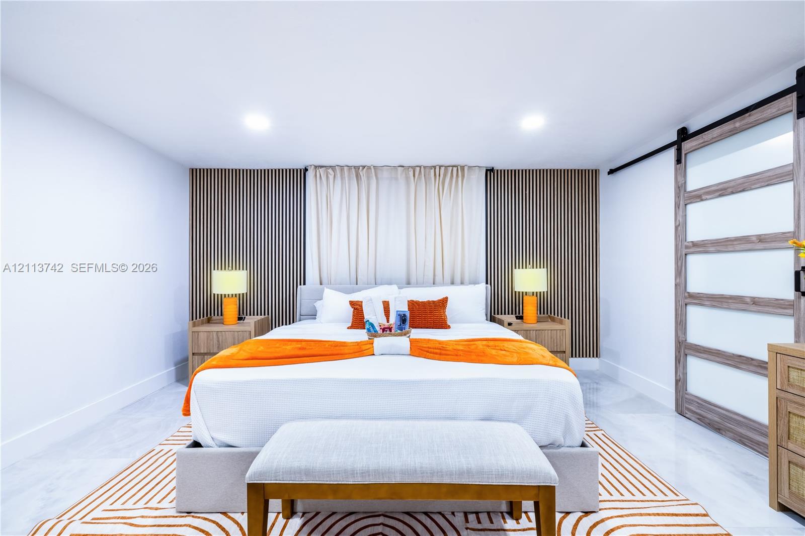 Interior space featuring vertical wood-slat accent wall paneling, recessed lighting, and a sliding barn-style door with frosted glass panels