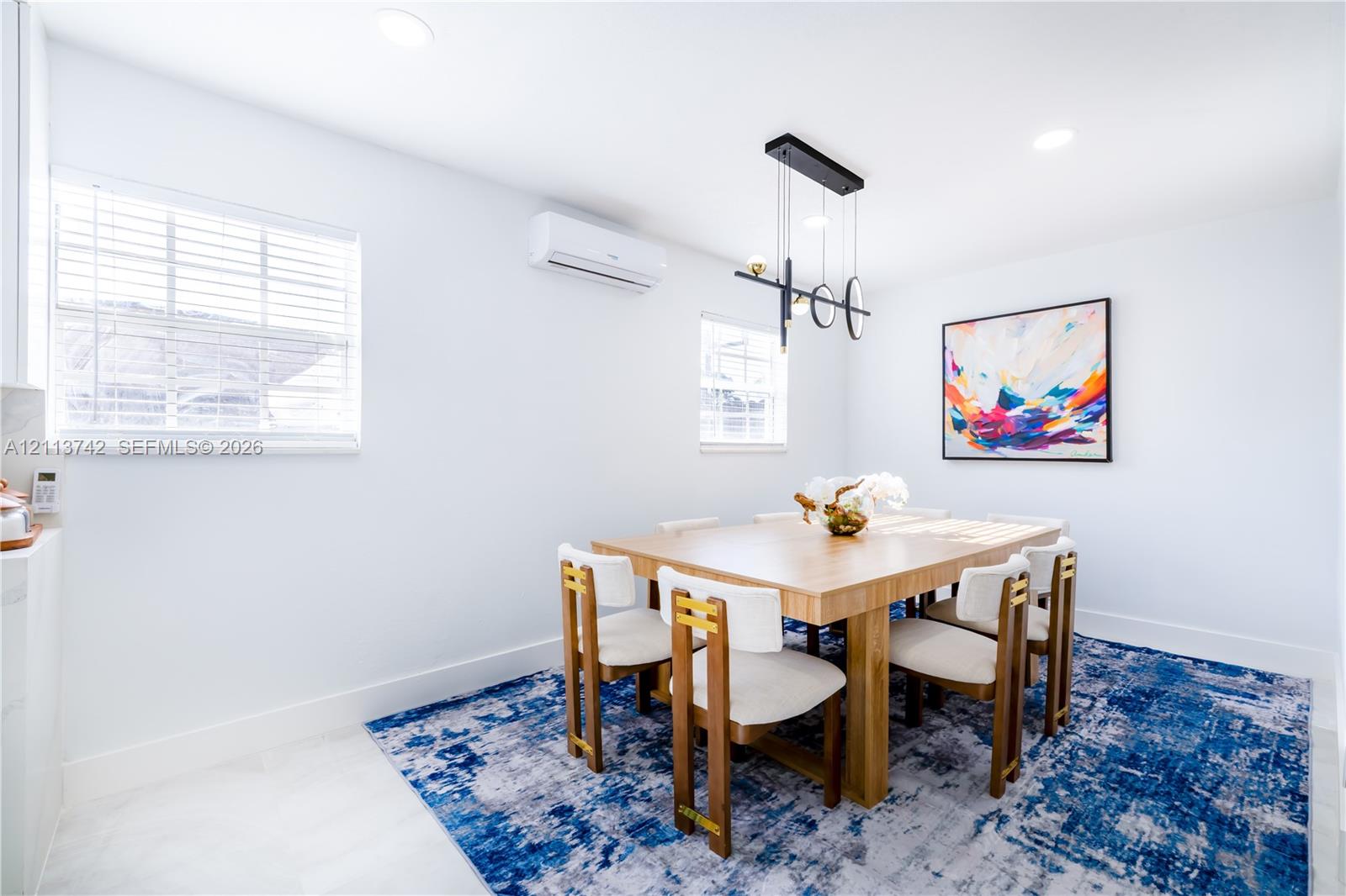 Interior space featuring recessed lighting, a modern multi-pendant geometric light fixture, wall-mounted ductless climate control unit, and window blinds