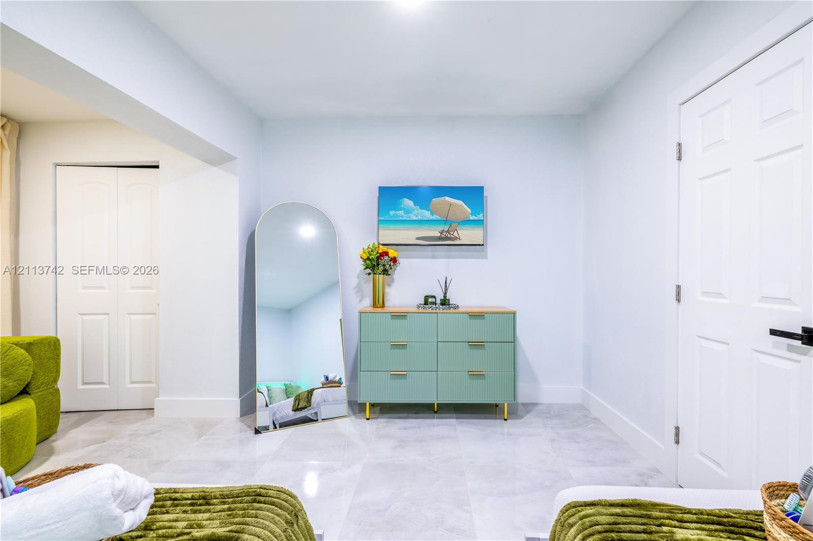 Neutral-toned interior featuring large-format tile flooring, recessed ceiling lighting, and two multi-panel interior doors with matte black hardware