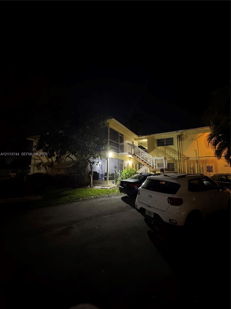 Multi-story exterior featuring a screened-in lanai, metal railings, and staircase access