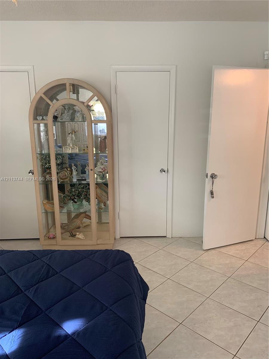 Neutral-toned ceramic tile flooring and white interior doors with brushed metal hardware