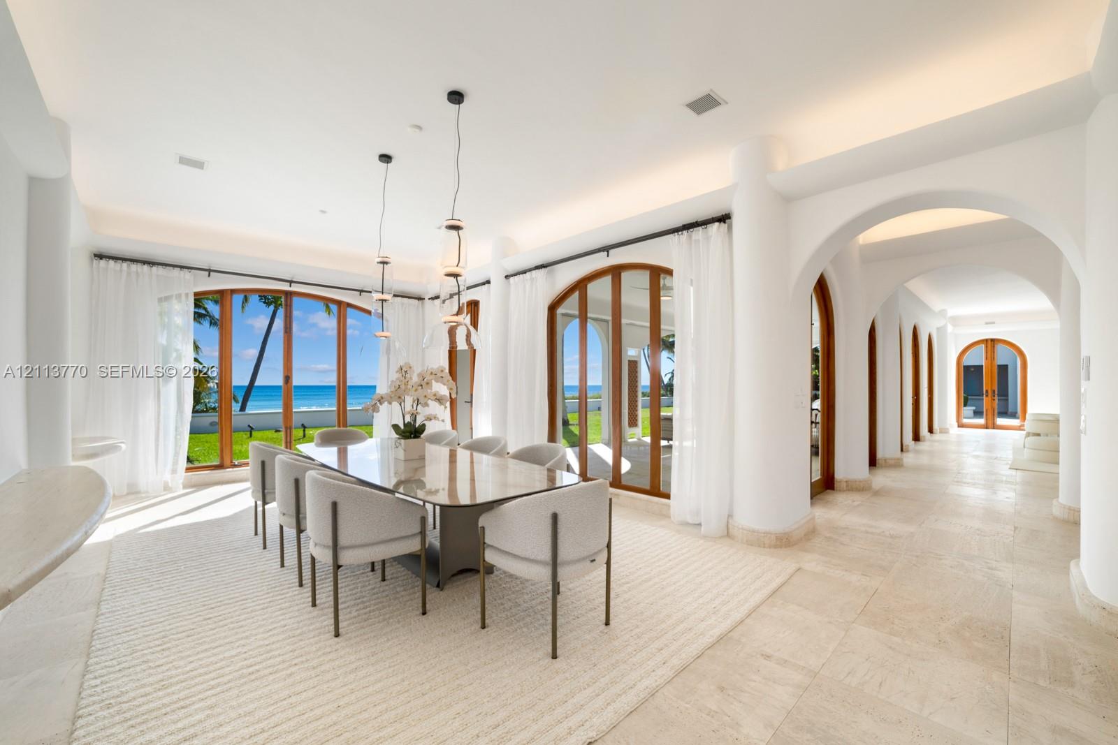 Open-concept area featuring stone flooring, arched architectural detailing, dual sets of arched wood-framed glass doors, and recessed cove lighting