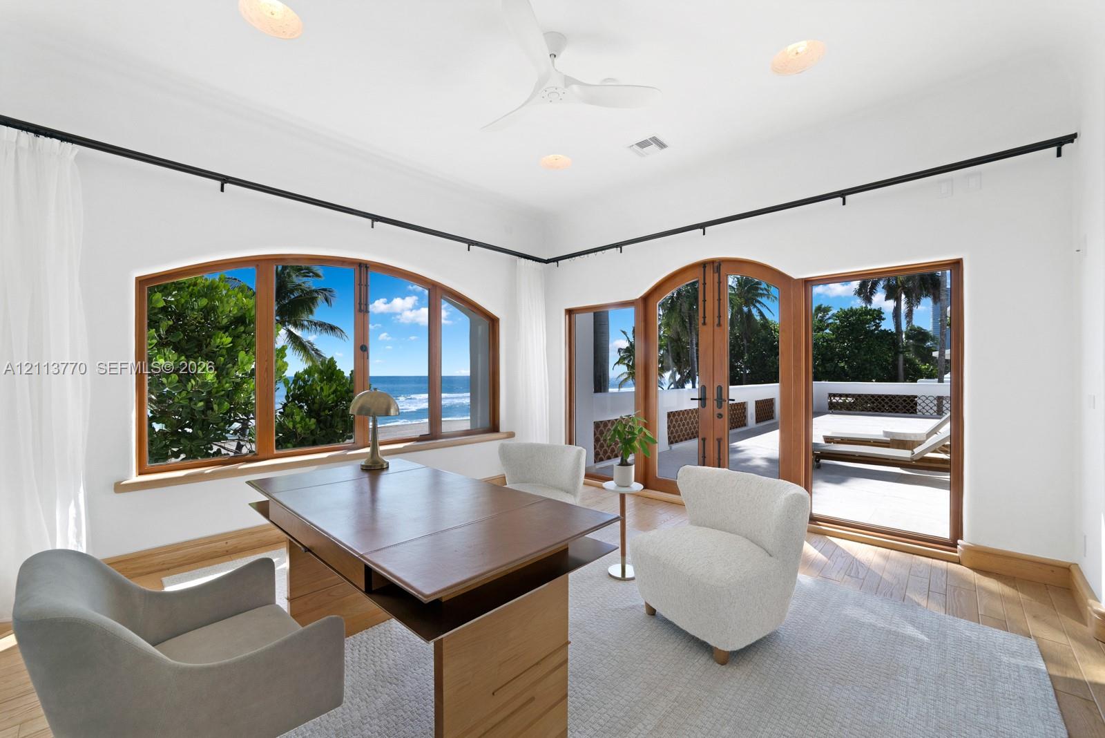 Arched wood-framed windows, double wood-framed glass doors, wood-finish flooring, recessed lighting, and a ceiling fan