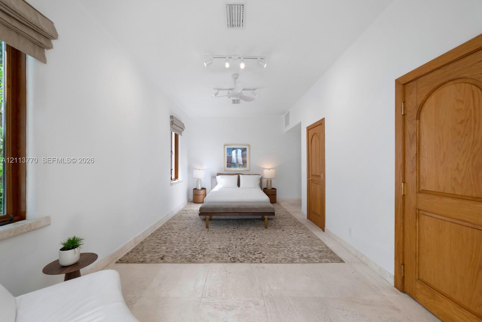 Neutral stone flooring, arched wood-finish doors, and adjustable track lighting