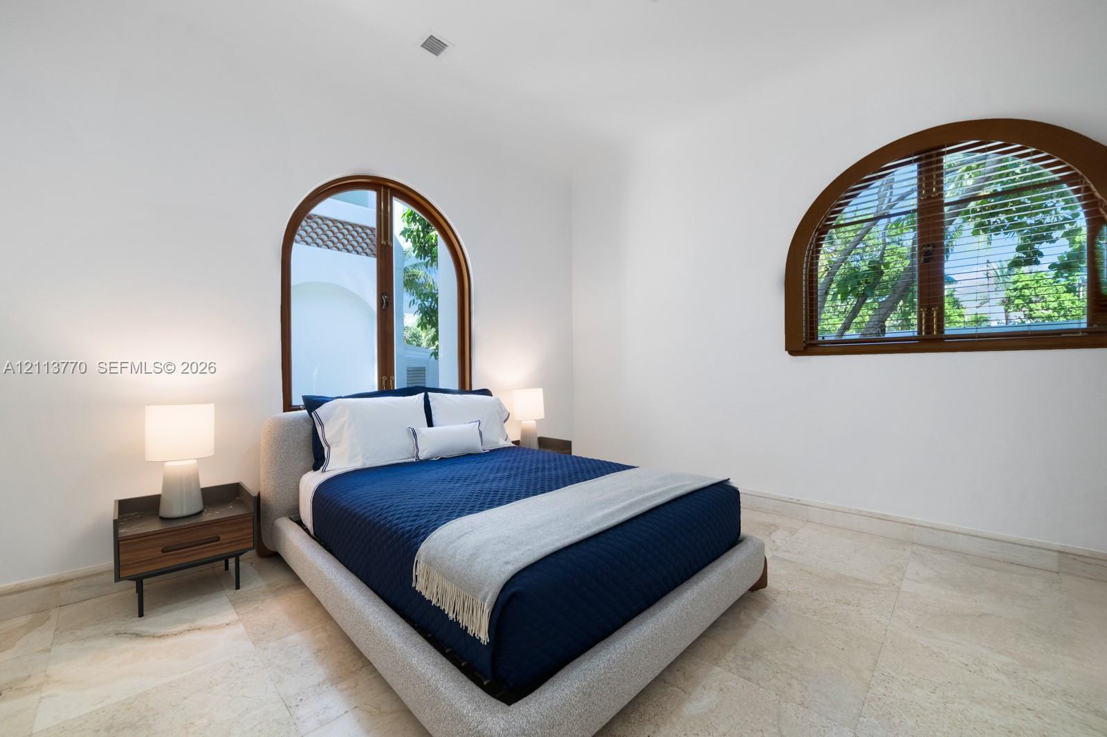 Natural stone flooring paired with dual arched windows featuring dark wood-finish framing